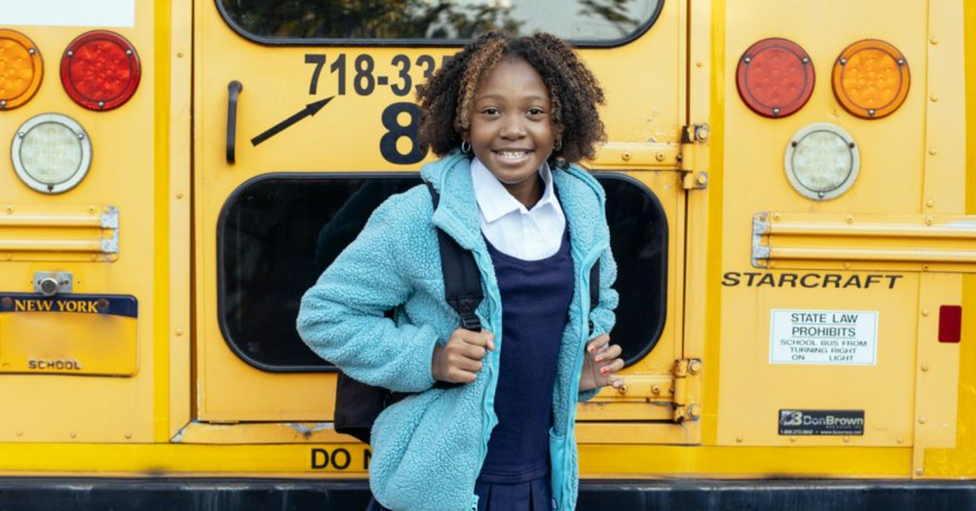 happy ethnic schoolchild near bus on city roadPhoto by Mary Taylor on Pexels.com