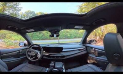 Interior view of 2027 Buick Enclave Sport Touring showing dashboard, leather seats, and infotainment touchscreen.