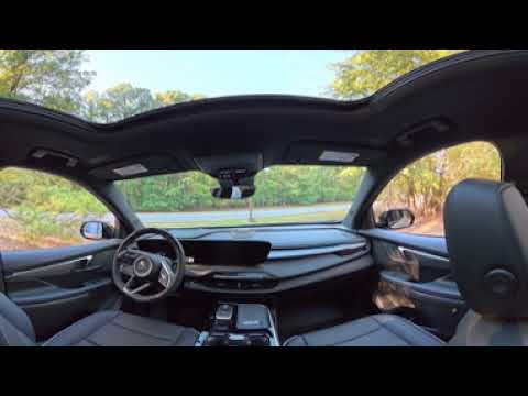 Interior view of 2027 Buick Enclave Sport Touring showing dashboard, leather seats, and infotainment touchscreen.