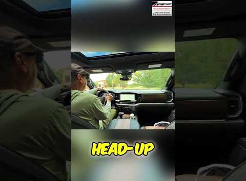 Driver testing a car head-up display on a dashboard to check for glare during daylight driving conditions.