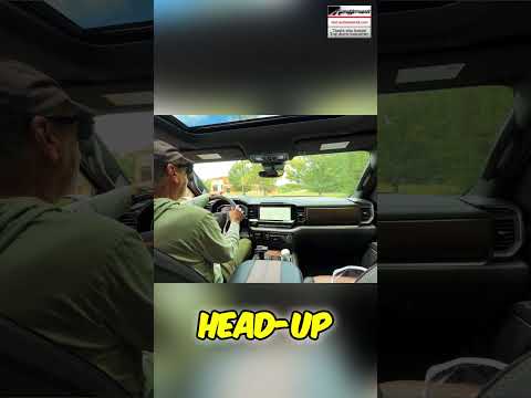 Driver testing a car head-up display on a dashboard to check for glare during daylight driving conditions.