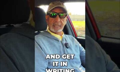 Car buyer sitting at a dealership desk looking concerned while a salesperson explains monthly payment options.