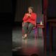 Stacey Abrams speaking at a podium at Harris-Stowe State University about democracy, voting, and leadership.