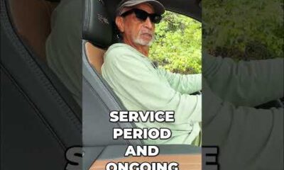 Driver smiling with hands off the steering wheel while using Super Cruise hands-free driving technology on a highway.
