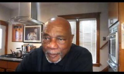 Al McFarlane hosting an interview segment for BlackPressUSATV with studio lighting and professional broadcast equipment.