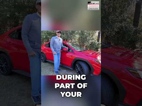Auto mechanic inside a car demonstrating how to turn off music to listen for tire noise during a vehicle test drive.