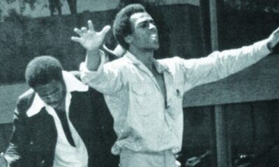 Black Panther Party co-founder Huey P. Newton raises his arms above a crowd of supporters. In his 1971 essay “Black Capitalism Re-Analyzed,” Newton argues that power means the ability of people to control their own destiny.