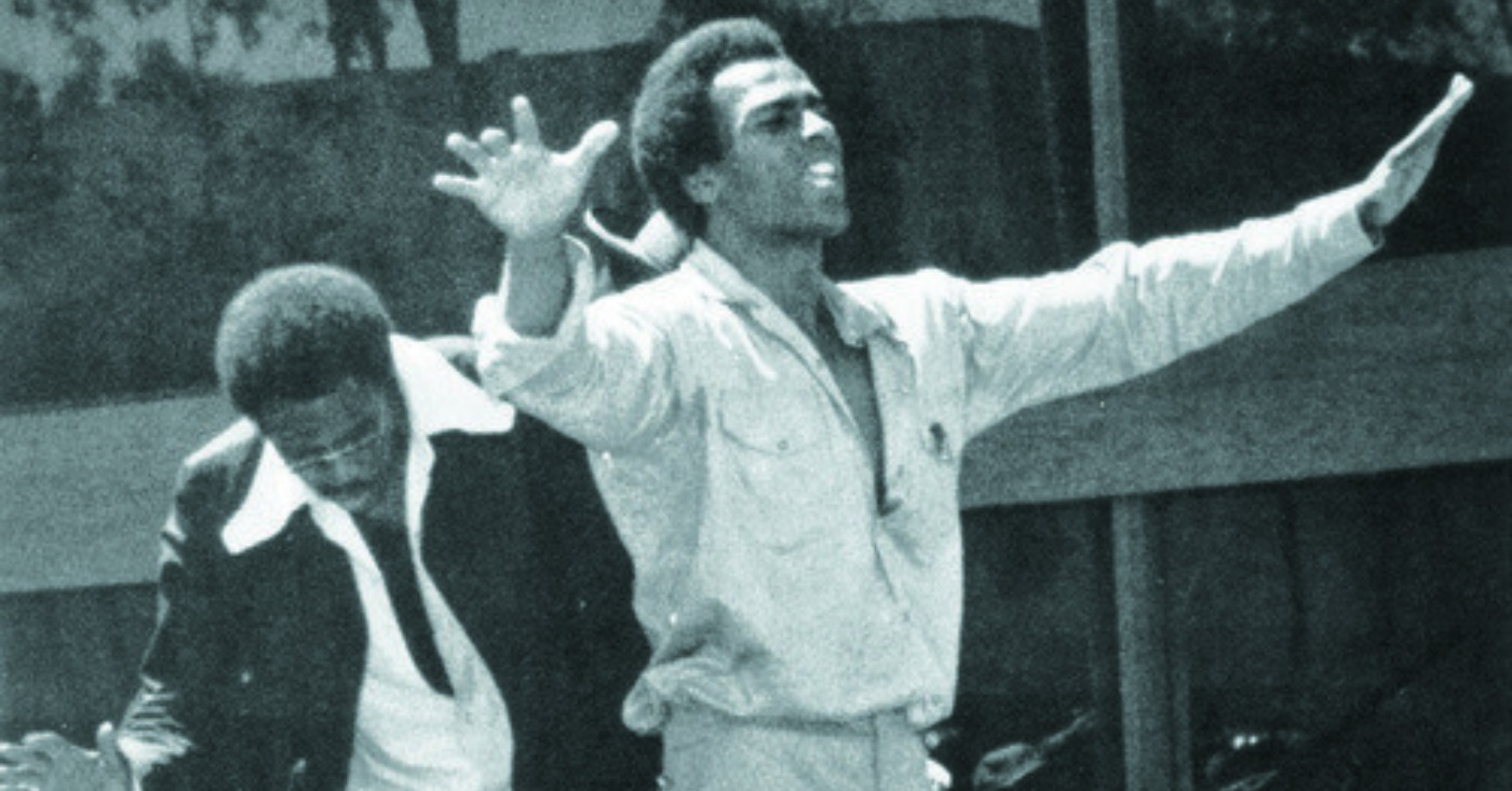 Black Panther Party co-founder Huey P. Newton raises his arms above a crowd of supporters. In his 1971 essay “Black Capitalism Re-Analyzed,” Newton argues that power means the ability of people to control their own destiny.