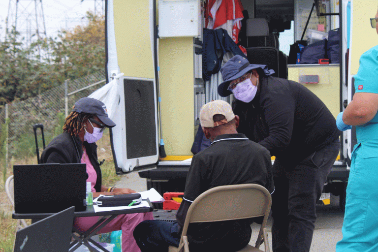 Bukola Olusanya, a nurse practitioner, provides street-level medical care to an unsheltered patient at the L.A. River. (Photo by Marion Apio)