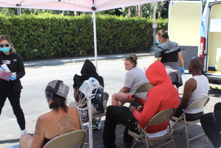 Unsheltered patients wait for medical evaluation from St. John’s mobile clinic team in Los Angeles. Photo by Marion Apio